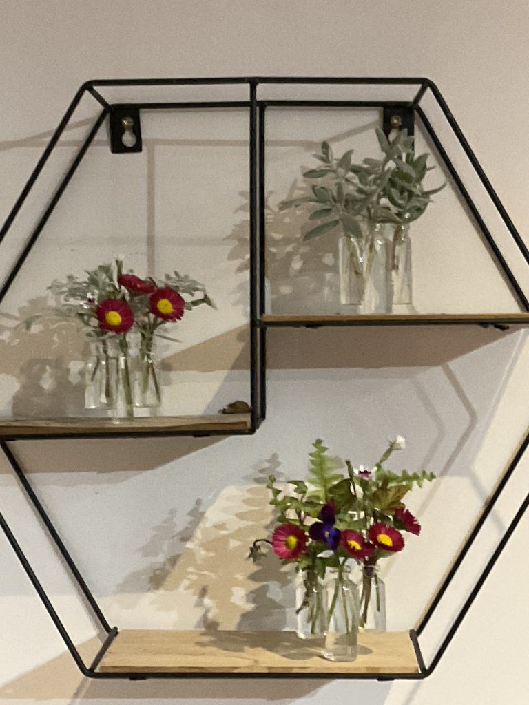 Miniature floral arrangements on a wall shelf.