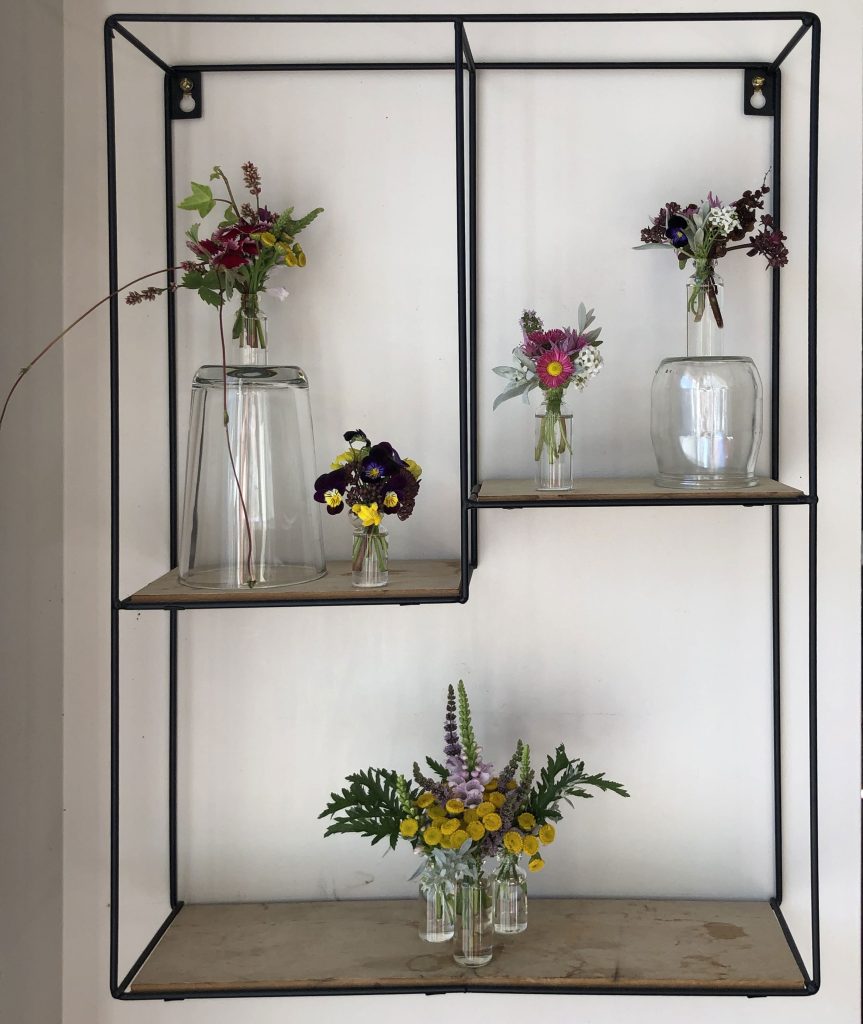 Miniature floral arrangements on a wall shelf.